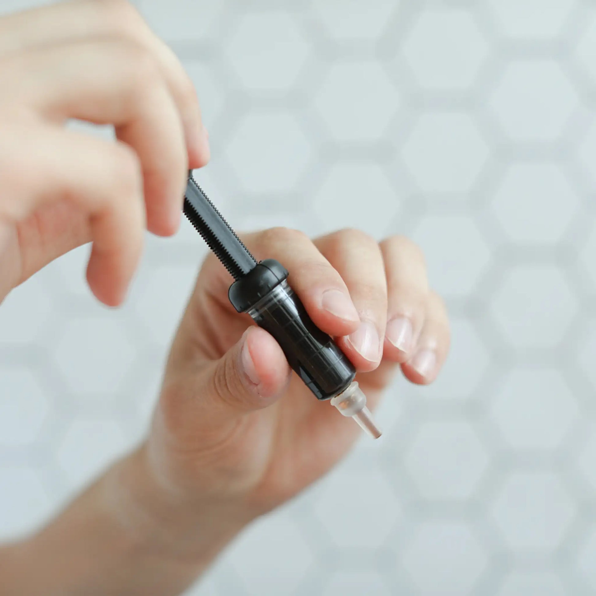 Nærbillede af en hånd, der holder en sort glasflaske med pipette til CBD-olie.
