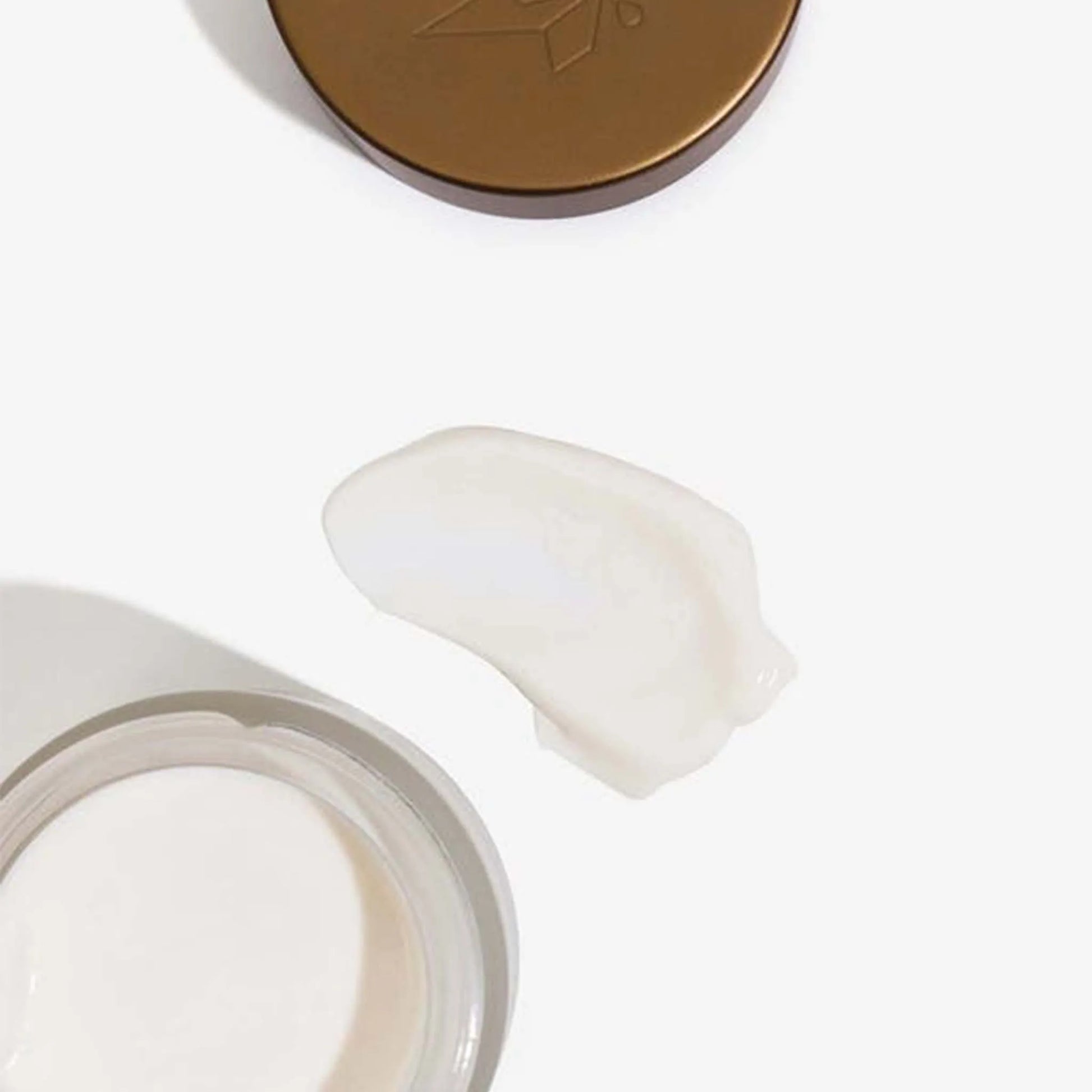 Æsken med CBD Anti-Aging Cream + Retinol ligger åben ved siden af ​​låget og en klat af cremen.