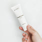 Hvid håndcremetube med teksten Hand Cream og CBD & Aloe Vera holdes af en hånd