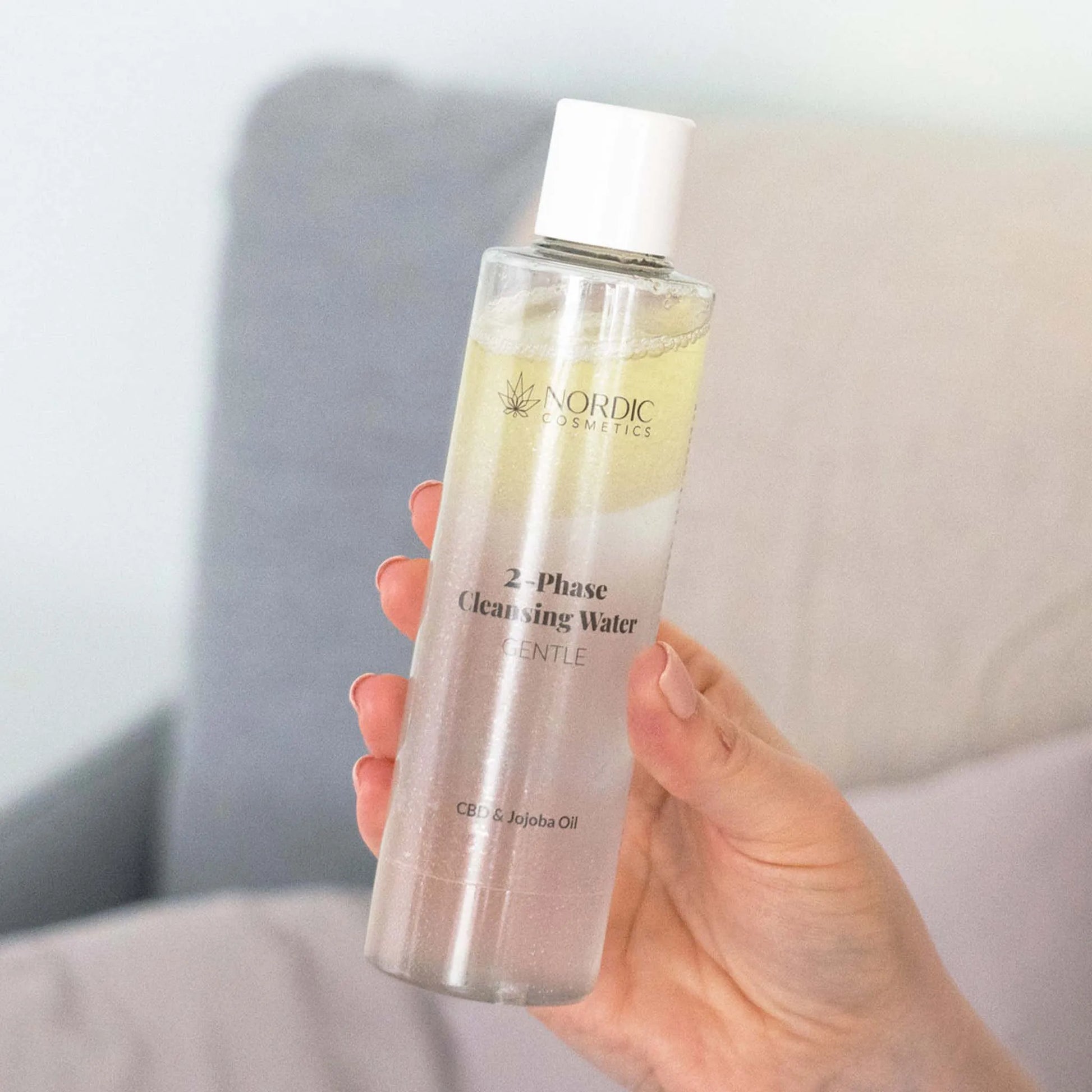 Nordic Cosmetics 2-Phase Cleansing Water med CBD og Jojoba-olie holdt i en hånd