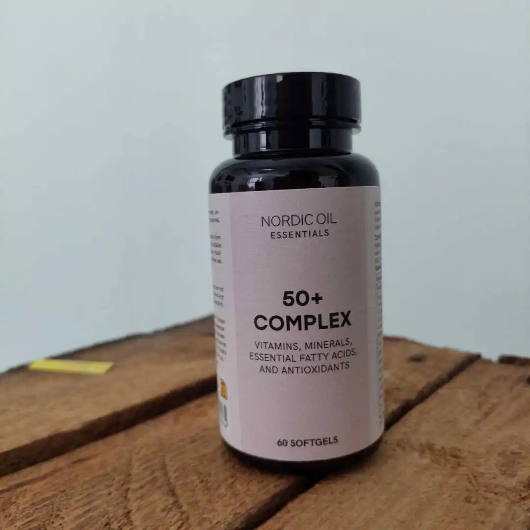 Nordic Oil Essentials 50+ Complex kosttilskud i flaske med sort låg stående på et træbord