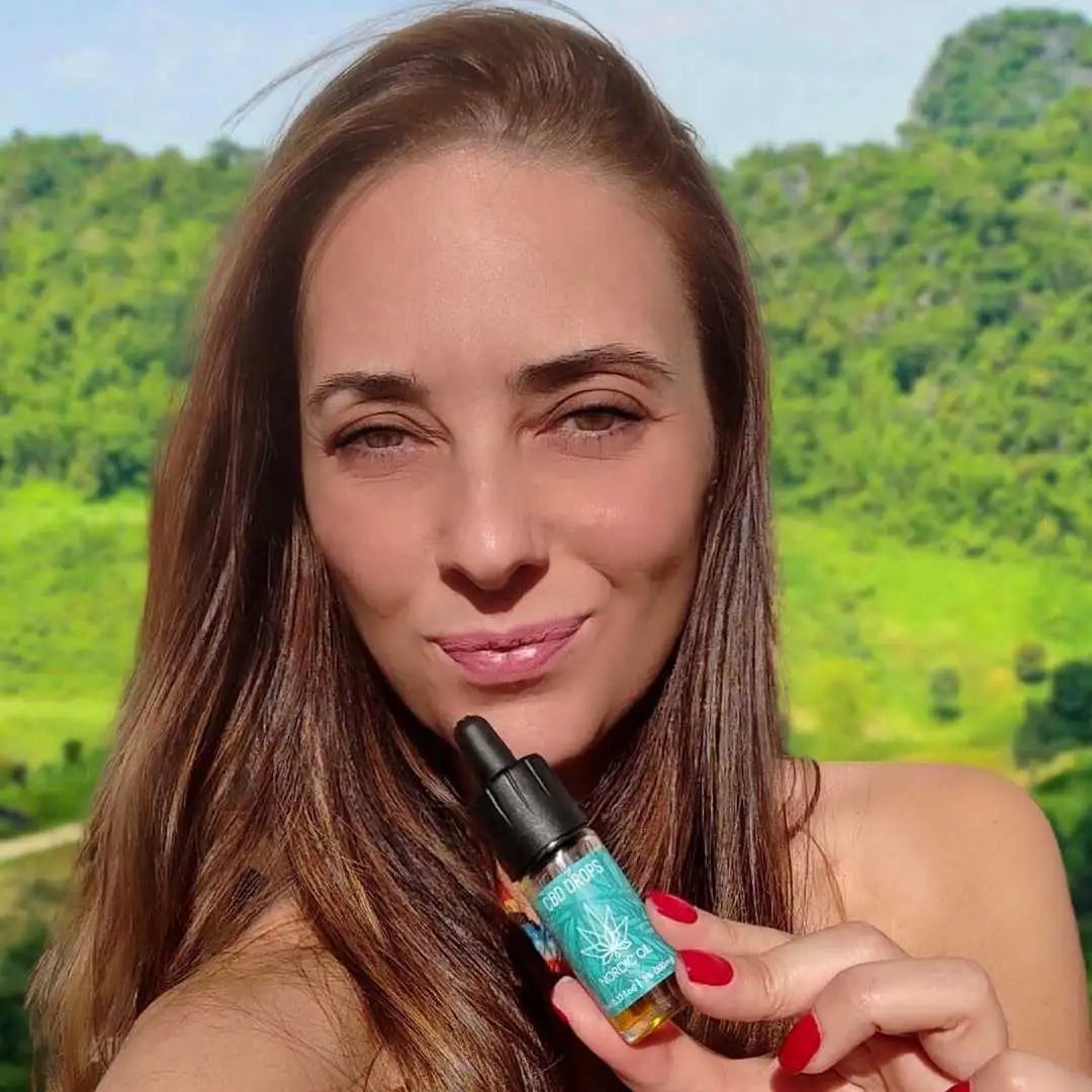 Kvindelig model viser CBD-dråber med dropper udenfor