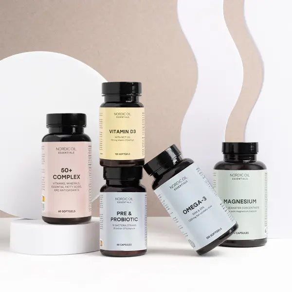 Fem Nordic Oil Essentials kosttilskud i forskellige flasker (50+ Complex, Vitamin D3, Pre & Probiotic, Omega-3, Magnesium) på en lys beige og hvid baggrund.