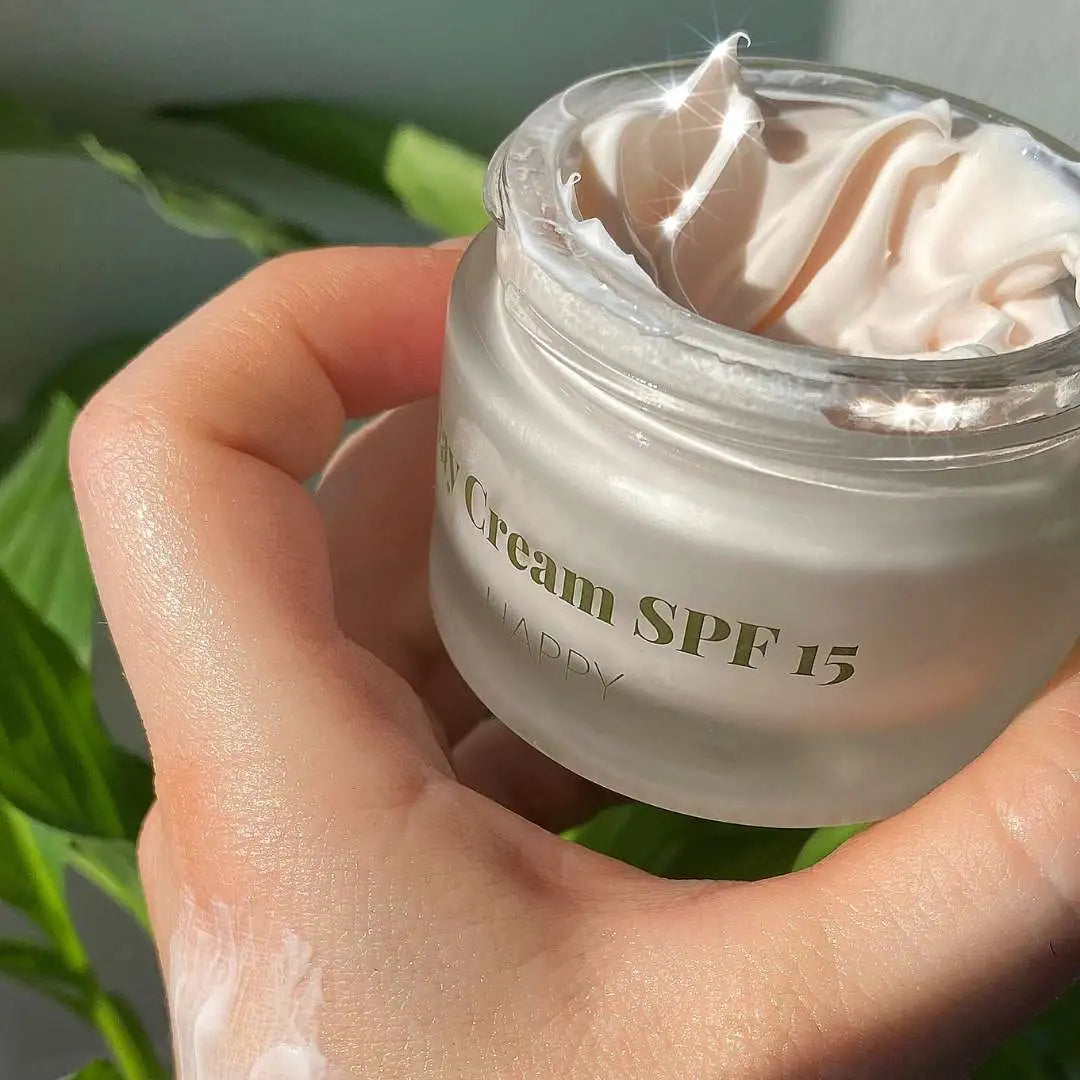 Nærbillede af en hånd, der holder en åben krukke med ansigtscreme SPF 15.