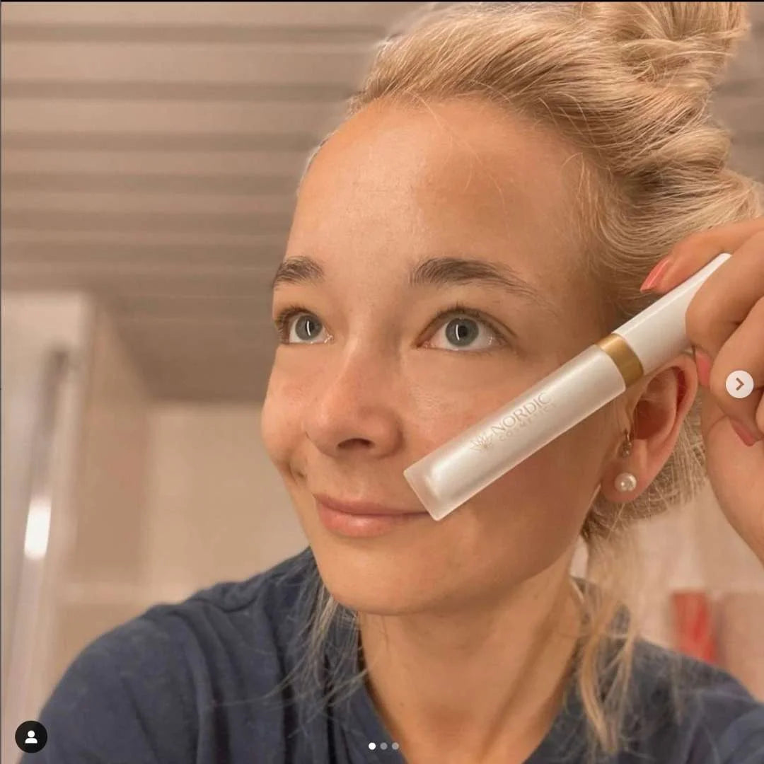 Kvinde, der påfører Nordic Oil-produkt ved kinden.