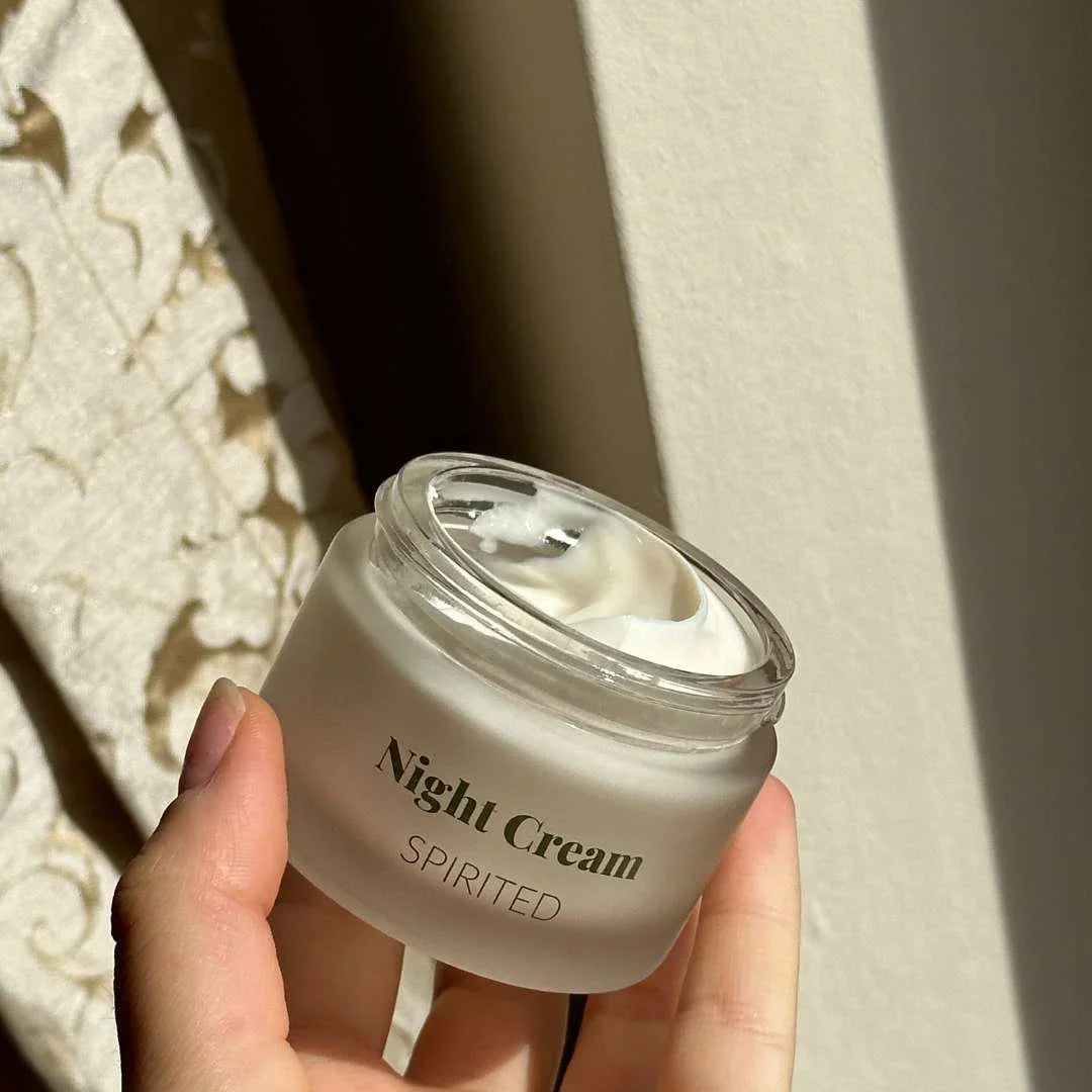 Natcreme Spirited i glaskrukke holdt af en hånd i sollys