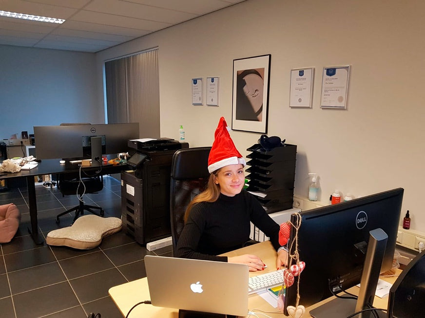 Foto af teammedlemmet ved skrivebordet med julehue 