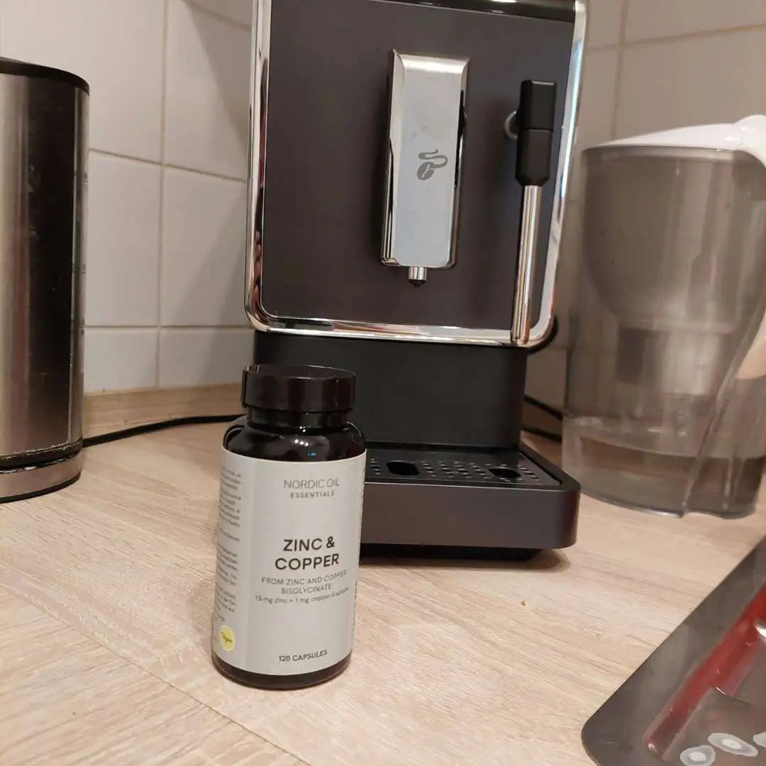 Nordic Oil Zink & Kobber kapsler på køkkenbordet ved kaffemaskinen.