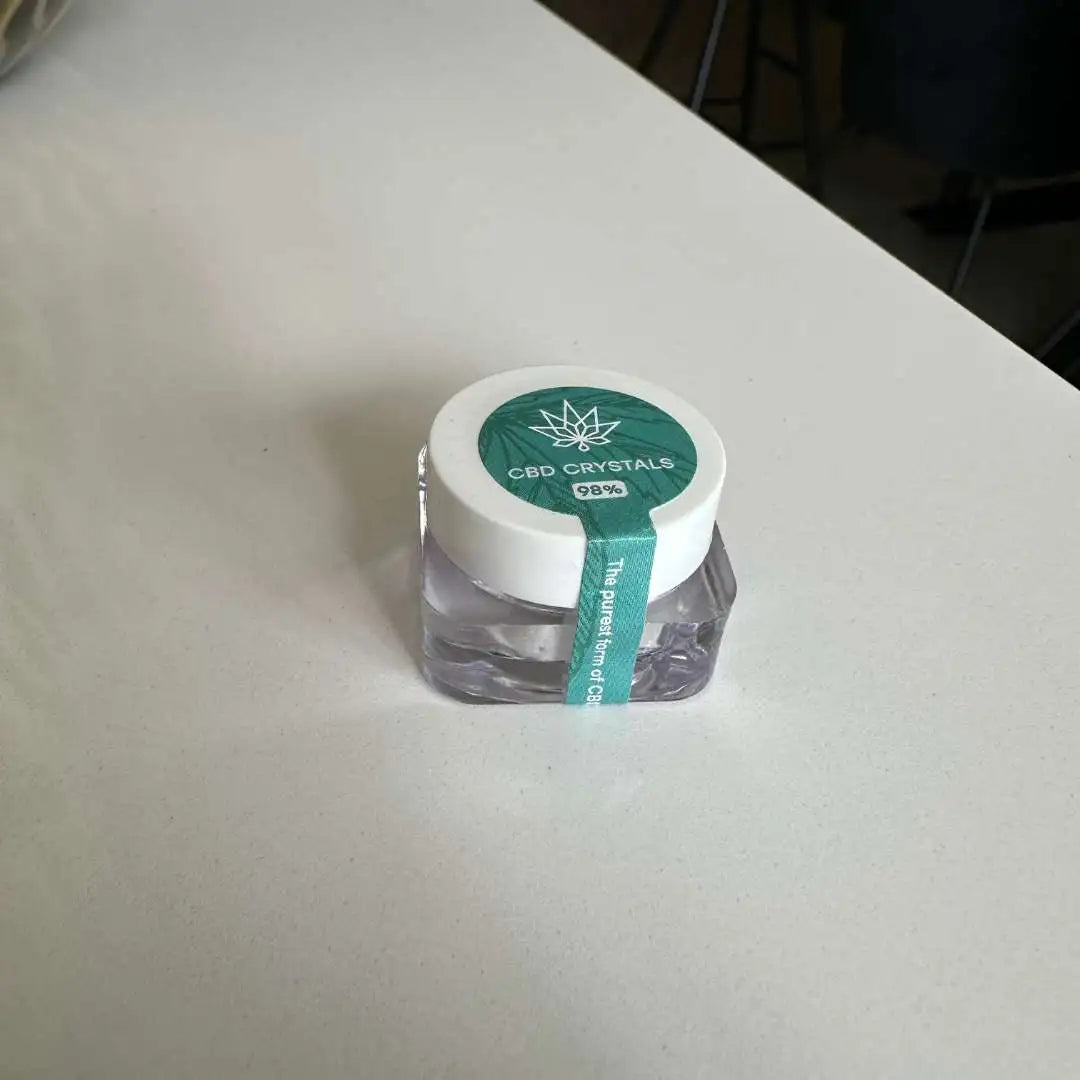 CBD-krystaller i lille glasbeholder med hvidt låg og grøn etiket.