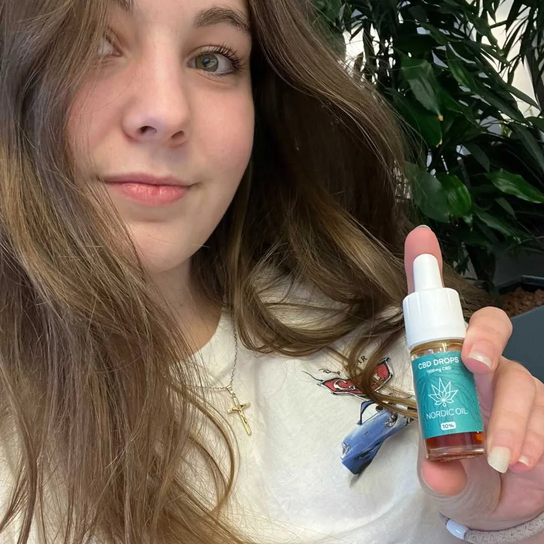 Nærbillede af en ung kvinde, der holder en flaske CBD-dråber fra Nordic Oil.