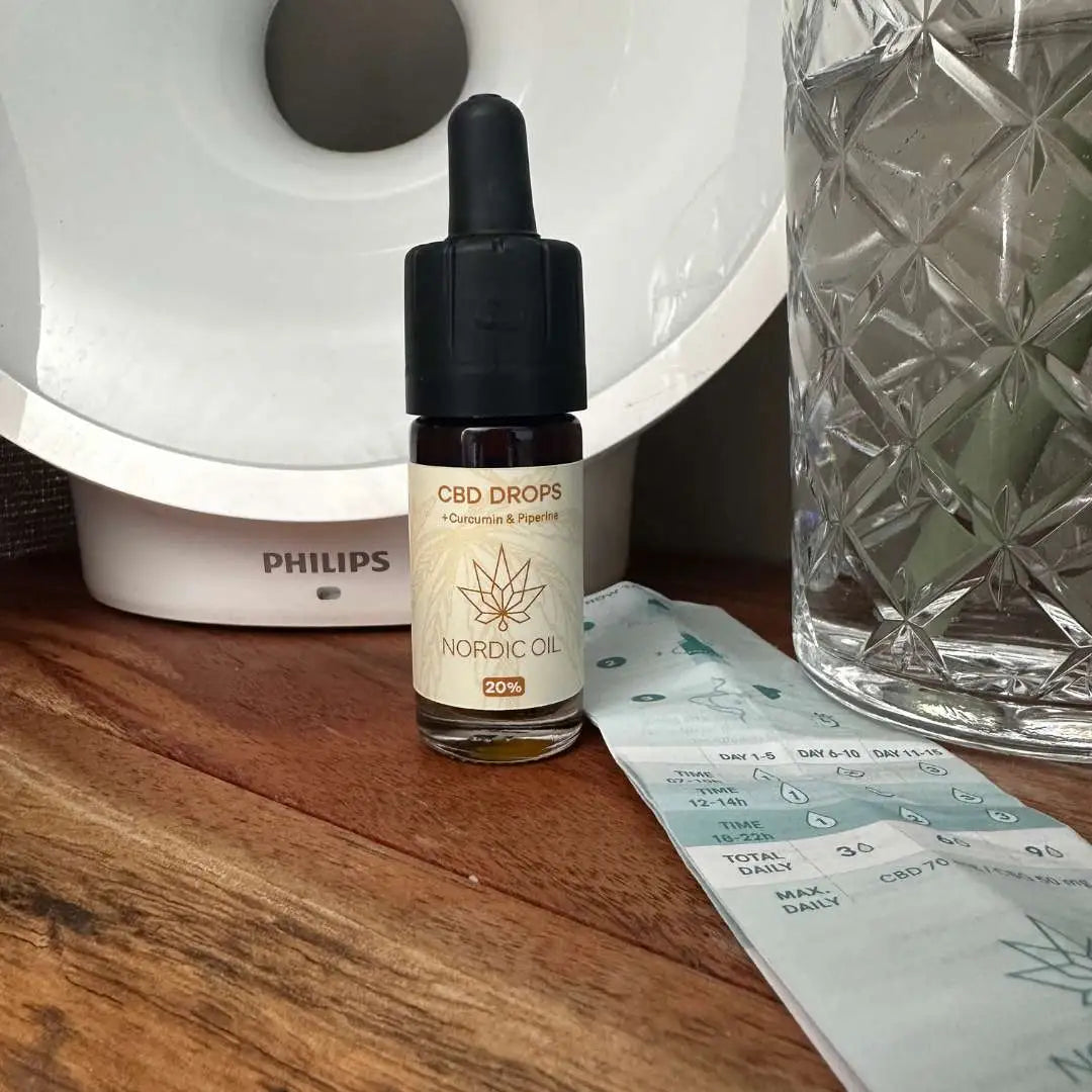 Nordic Oil CBD-dråber med dropper på træbord ved glasvase
