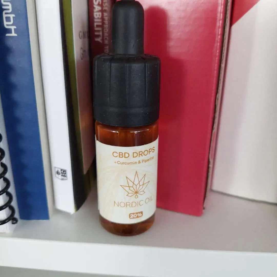CBD-dråber fra Nordic Oil med curcumin og piperin på boghylde