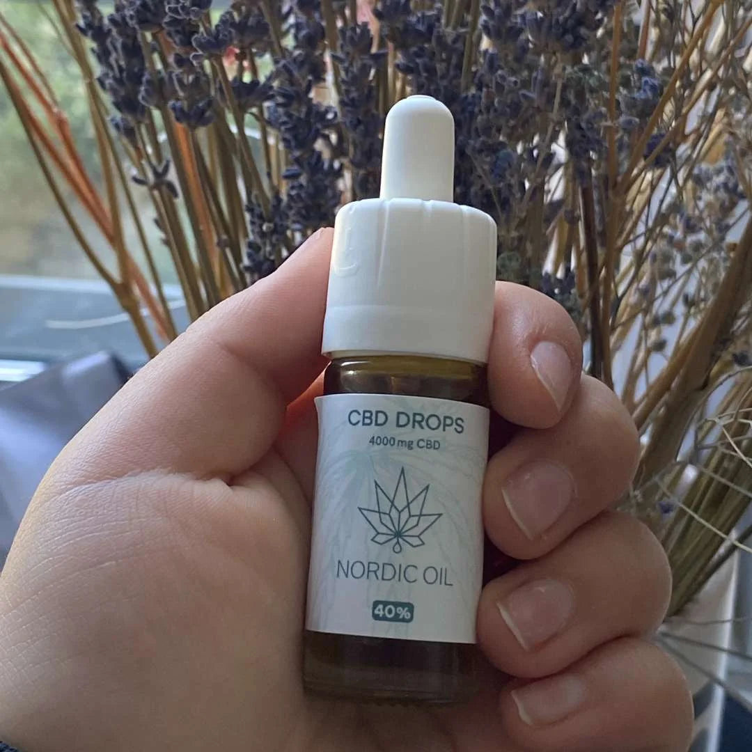 Nordic Oil CBD-drops flaske med dropper, 4000 mg CBD, holdes af en hånd med lavendel i baggrunden.