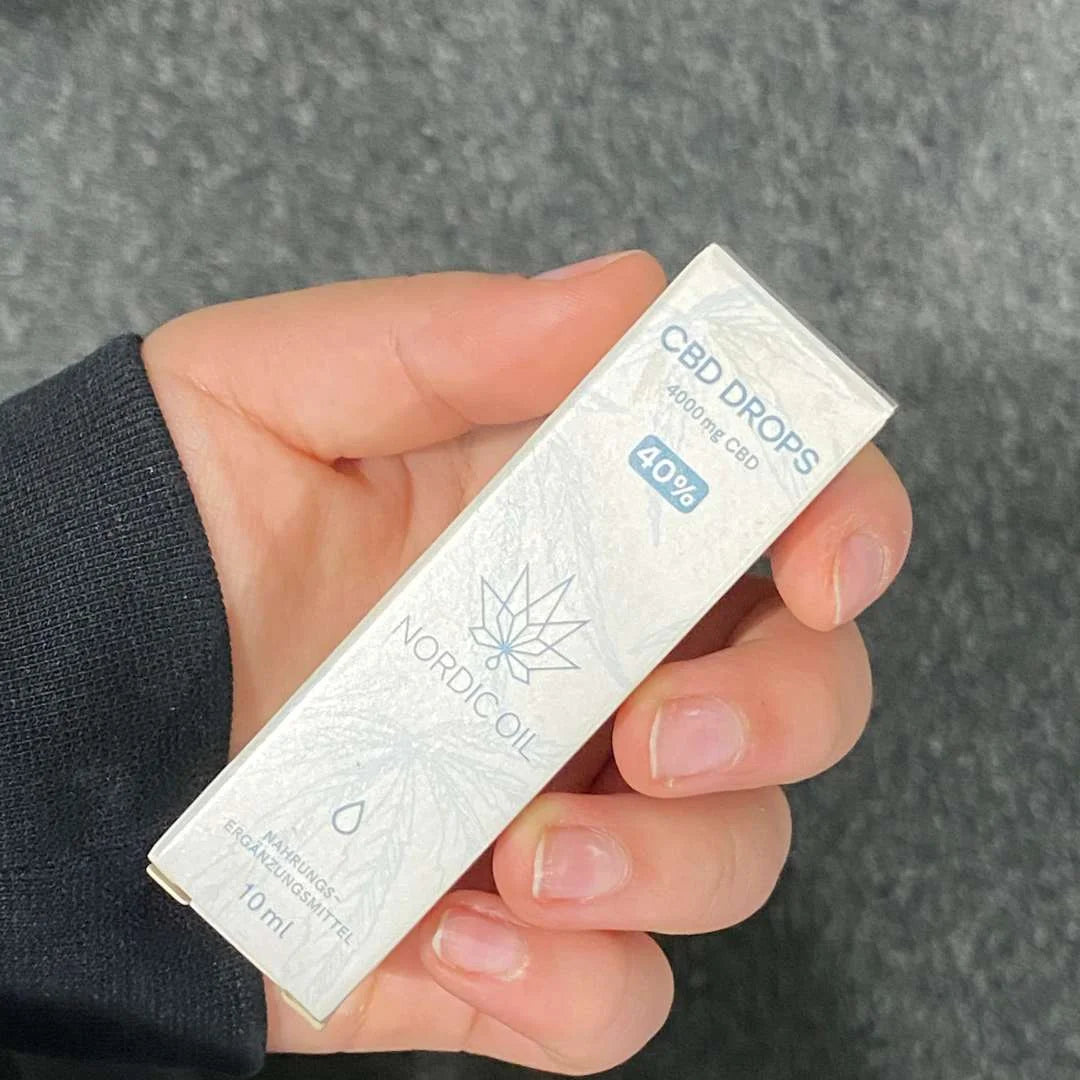 Hånd omkring en hvid æske med Nordic Oil CBD Drops (10 ml, 4000 mg CBD).