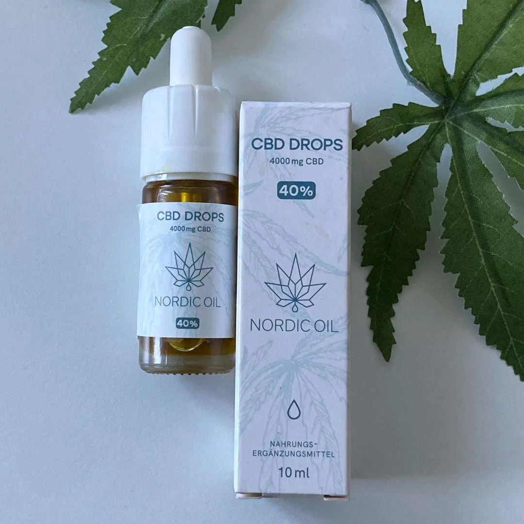 CBD-dråber og æske fra Nordic Oil med 4000 mg CBD og 40% mærkat, foran grønne cannabisblade