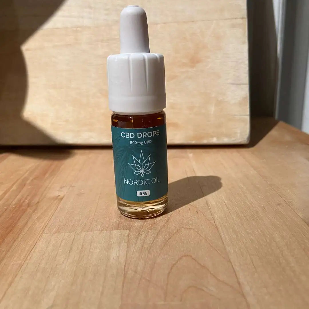 CBD-drops flaske fra Nordic Oil (500 mg CBD) med dropper på træbord.
