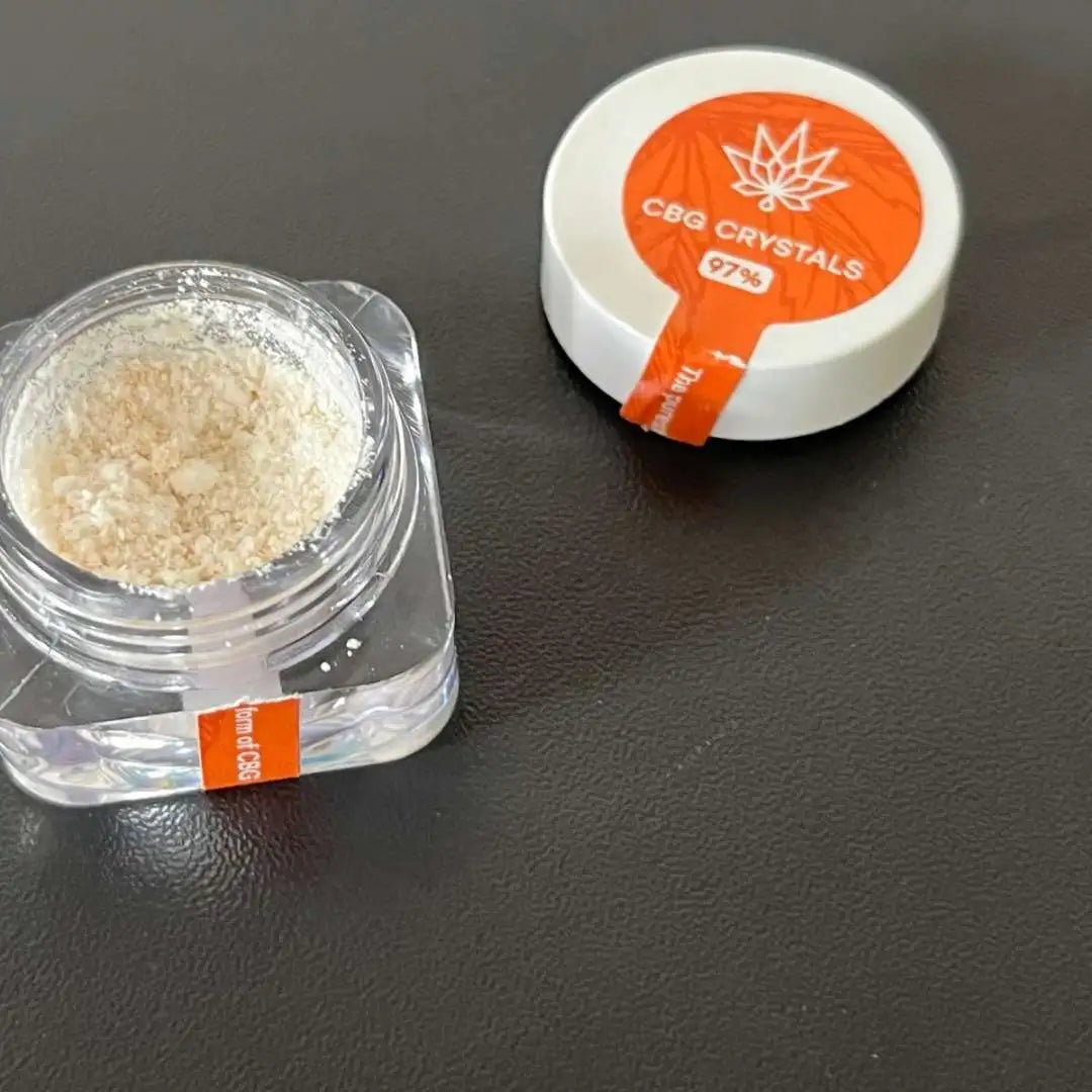 CBG-krystaller i gennemsigtig beholder ved siden af hvid rund krukke med orange etikets