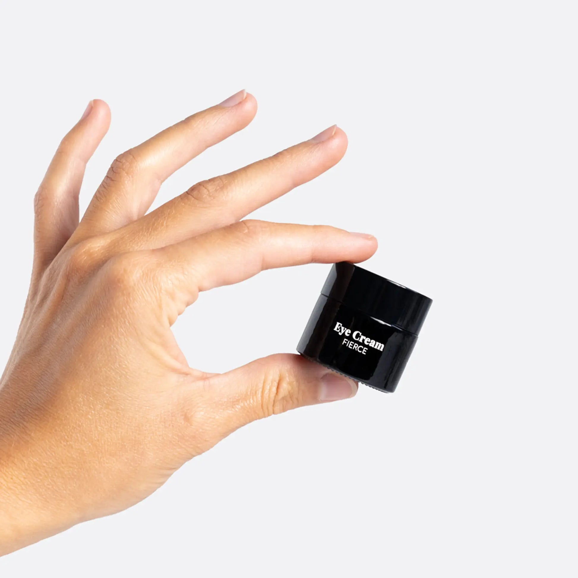En hånd holder en lille sort øjencremekrukke med teksten Eye Cream Fierce.