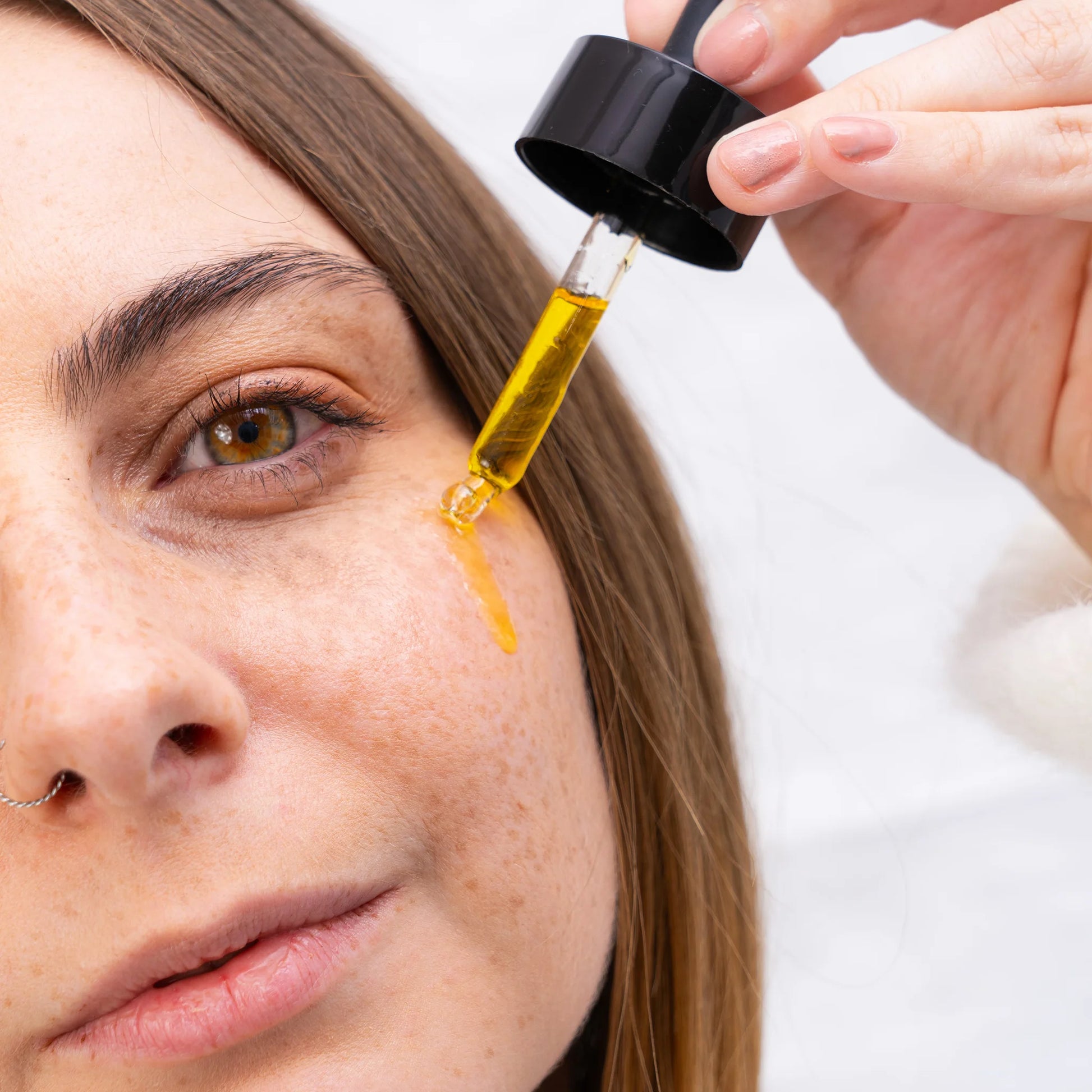 Nærbillede af en person, der drypper CBD-olie ved øjet med en dropper.