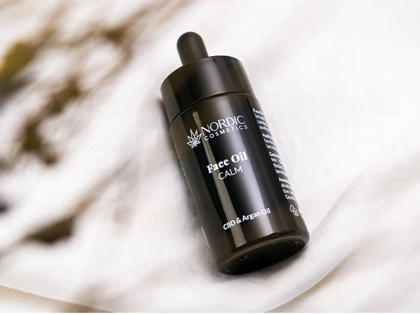 Nordic Cosmetics Face Oil CALM med CBD og arganolie i mørk glasflaske med dropper på hvidt stof