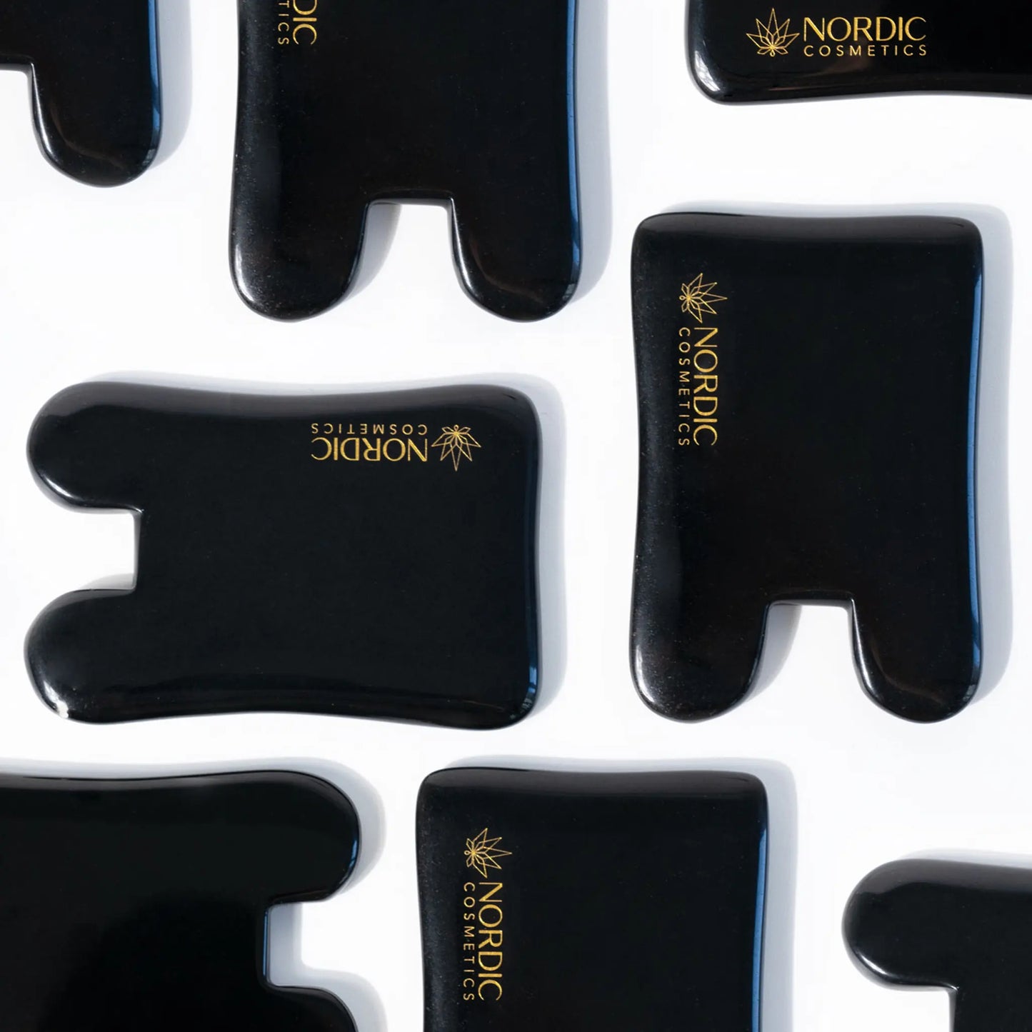 Sort glossy kosmetikemballage med gyldent Nordic Cosmetics-logo på hvid baggrund