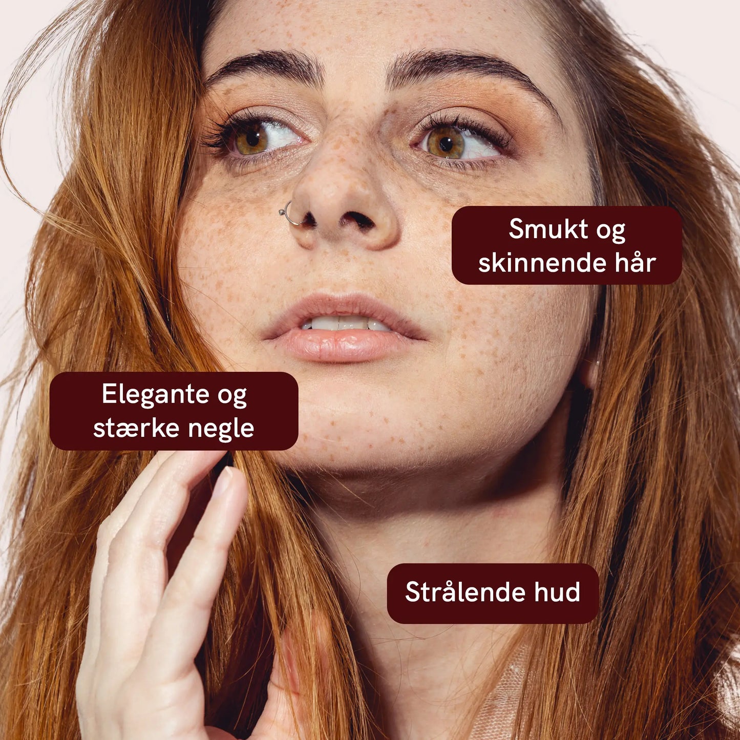 Nærbillede af en kvinde med fregner og rødt hår; tre tekstbobler viser budskaber om smukt og skinnende hår, elegante og stærke negle og strålende hud.