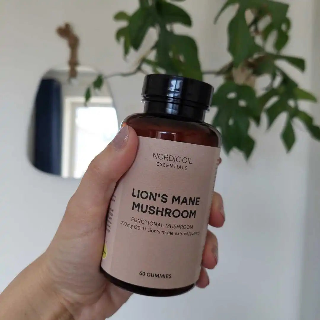 Hånd der holder en flaske Nordic Oil Essentials Lion's Mane Mushroom kosttilskud (60 gummies).