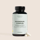 Nordic Oil Essentials Magnesium Complex-flaske med to kapsler ved siden af