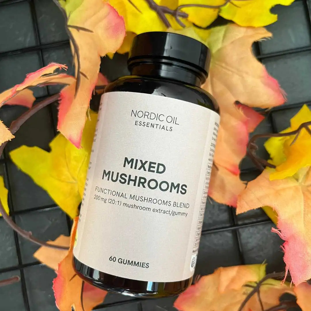 Flaske med Nordic Oil Essentials Mixed Mushrooms gummies (60 stk) omgivet af efterårsblade.