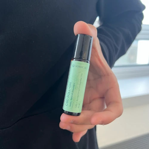 Nærbillede af CBD-roll-on olie i grøn flaske holdt i hånd