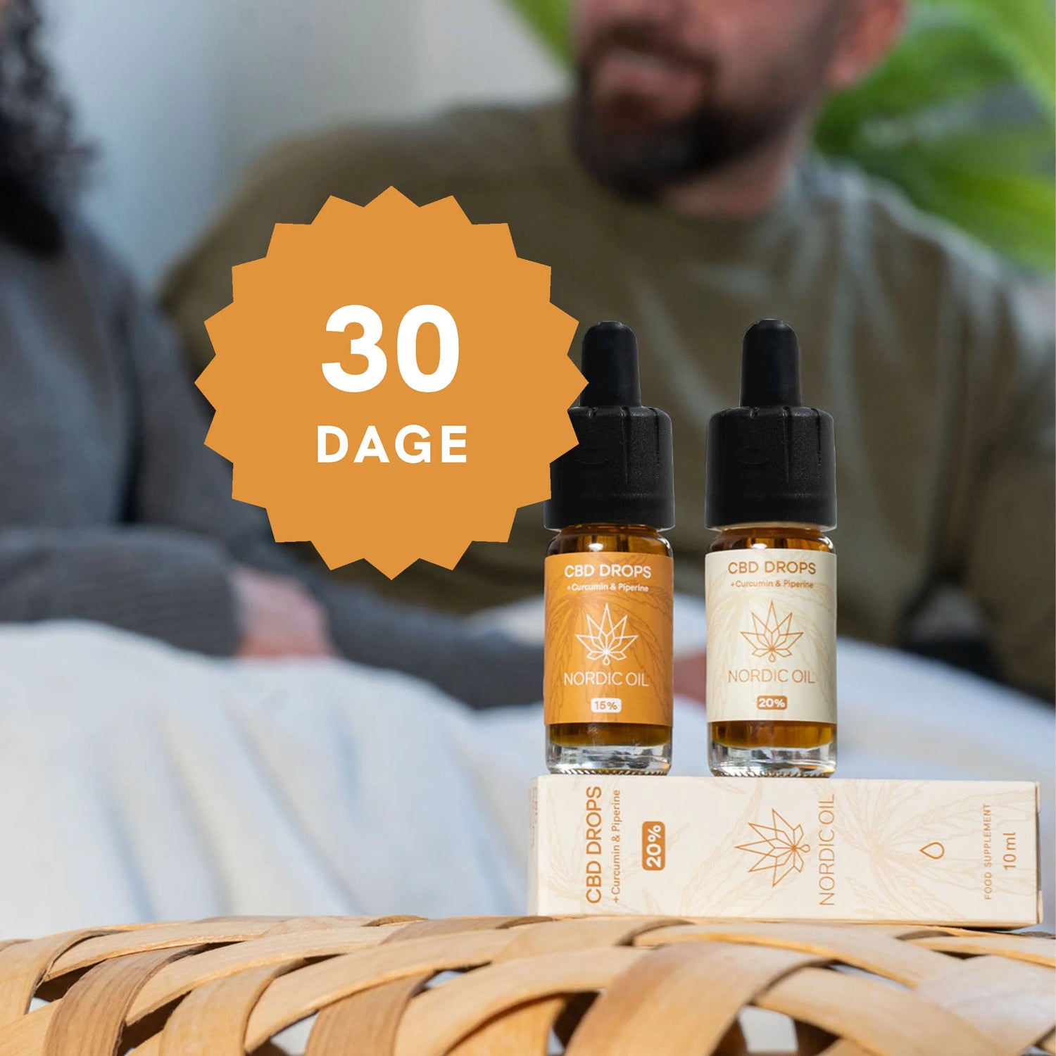 To CBD-drops-flasker fra Nordic Oil med en stor orange '30 DAGE'-badge foran, placeret på en emballagekasse på et flettet underlag.