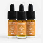 Tre CBD-dråber-flasker i amber glas med sorte dropper-kapper og orange etiketter