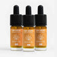 Tre CBD-dråber-flasker i amber glas med sorte dropper-kapper og orange etiketter