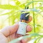 CBD-dråber i glasflaske med etiketten CBD DROPS holdes af en hånd blandt cannabisblade.