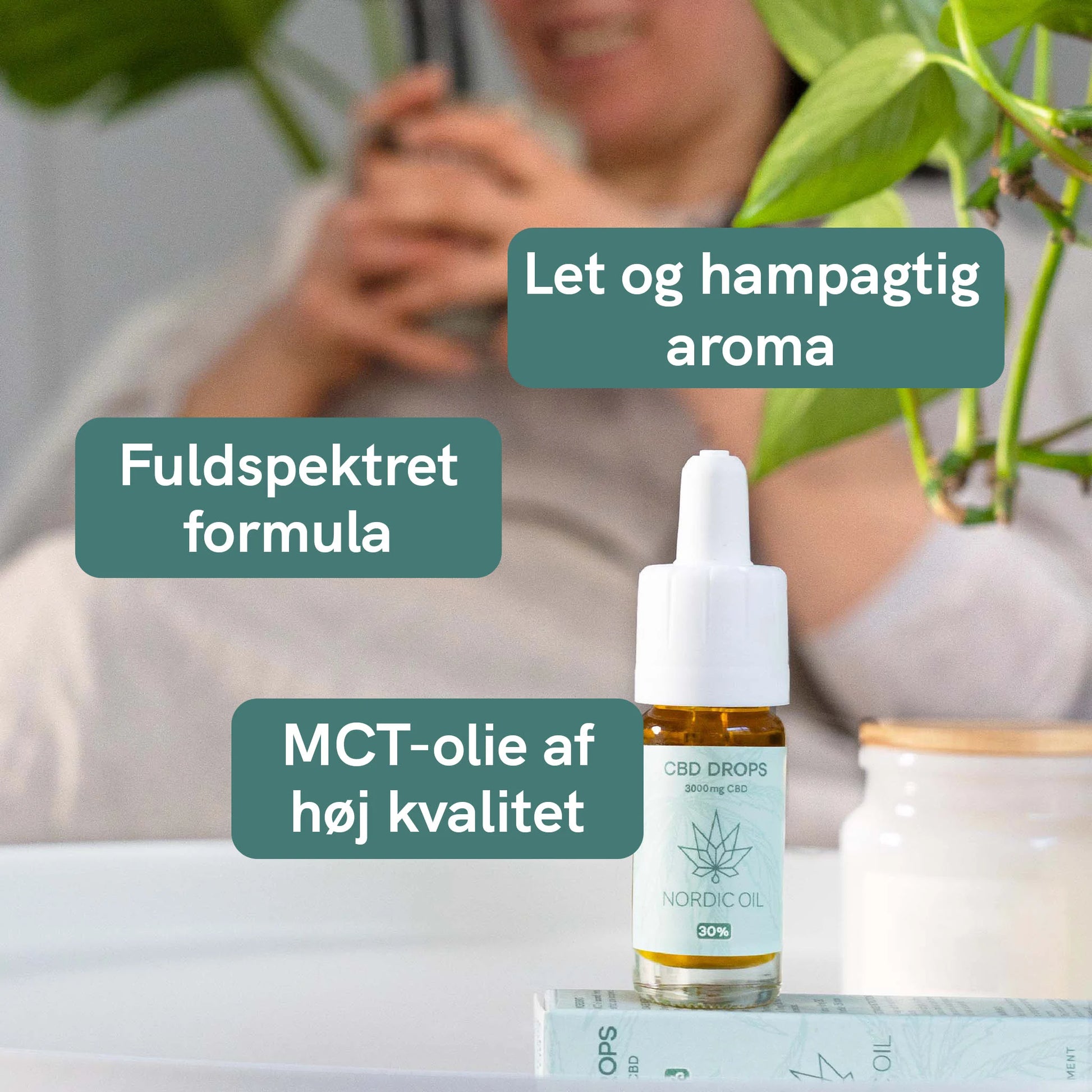 CBD-dråber i glasflaske fra Nordic Oil på et bord med en grøn plante i baggrunden