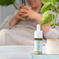 CBD-drops flaske med dropper fra Nordic Oil på bordet med grøn plante i baggrunden