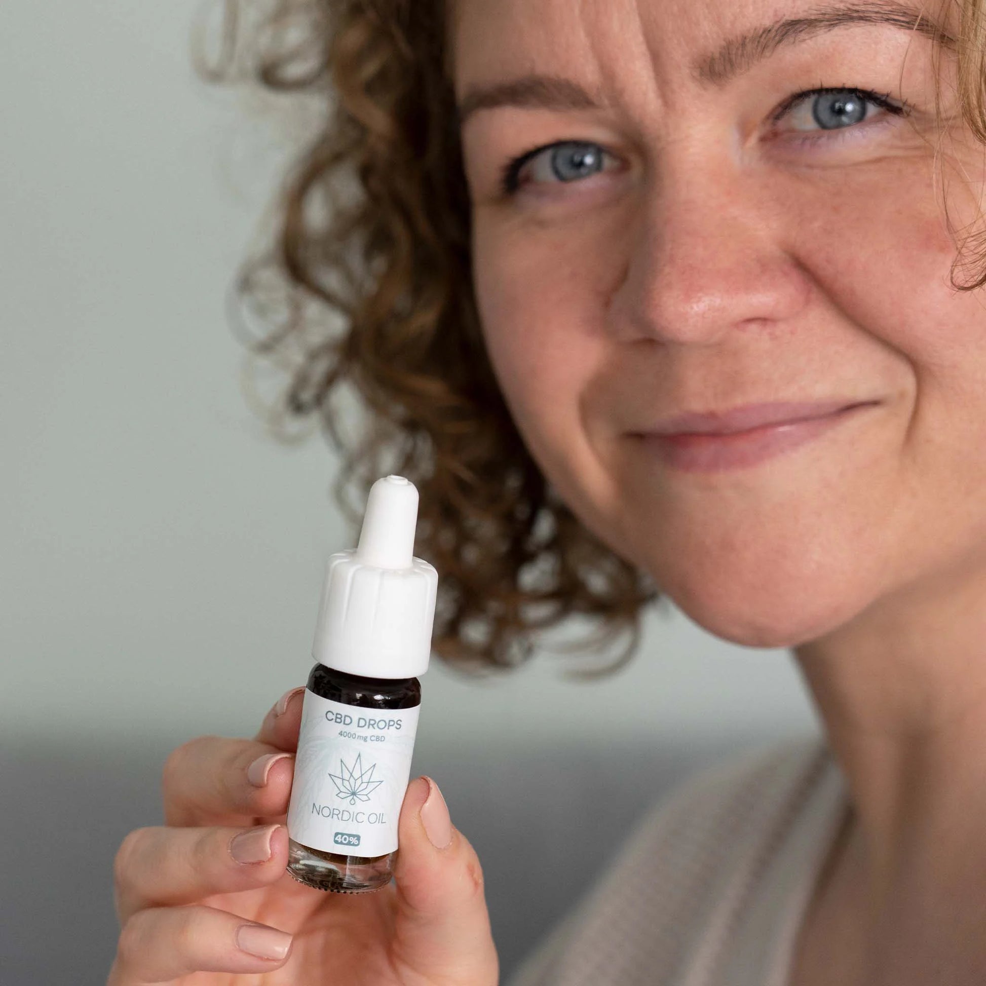 Kvindelig model holder en lille flaske CBD-dråber fra Nordic Oil med dropper