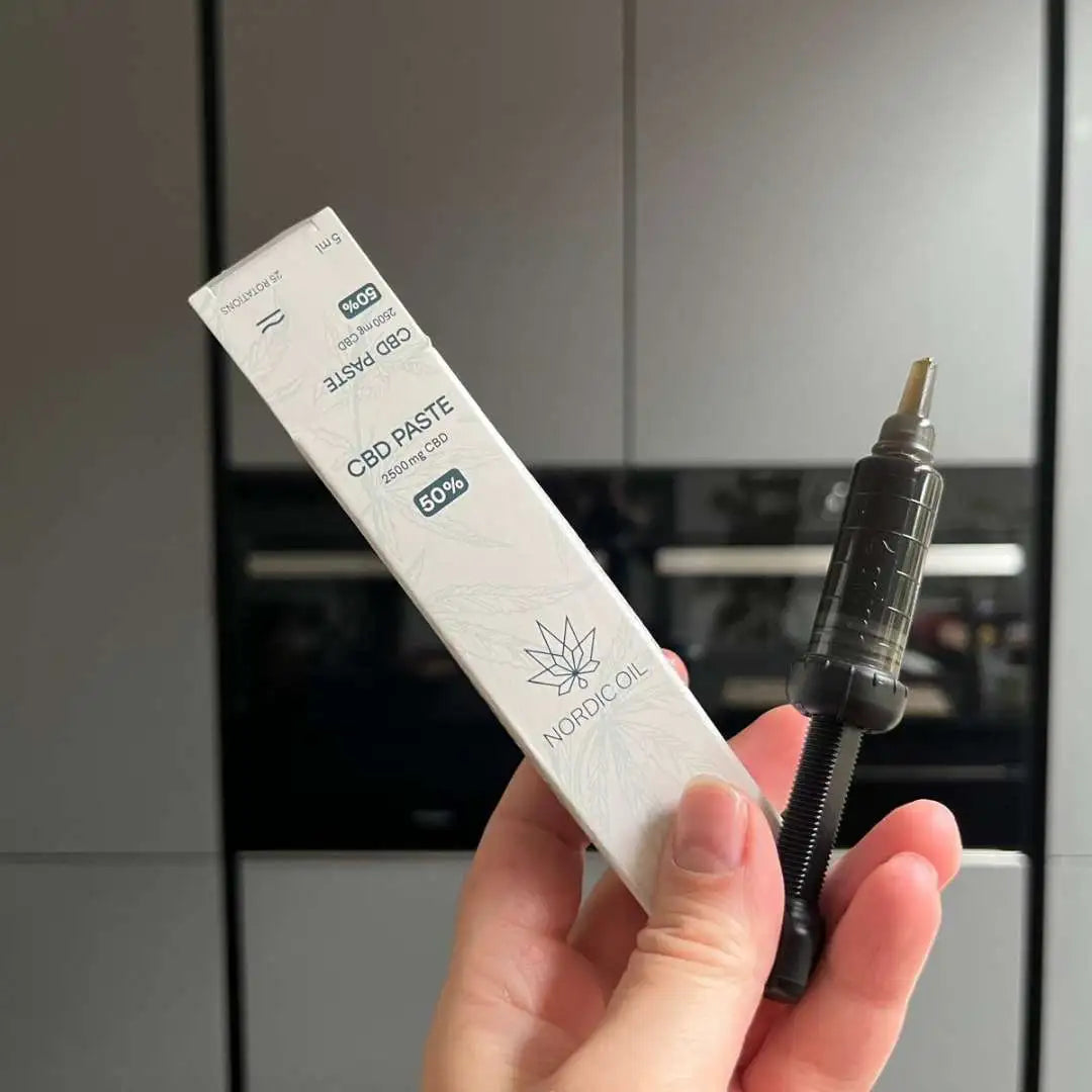 Hånd holder Nordic Oil CBD Paste-æske med 50% CBD og en doseringssprøjte
