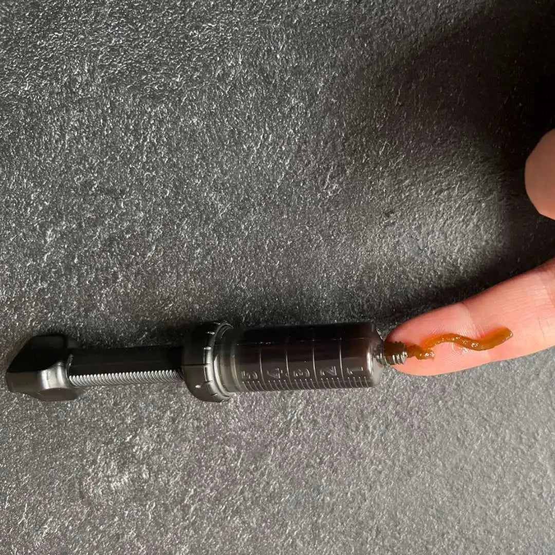 Dropperflaske med CBD-olie og en finger med olie på en mørk overflade.