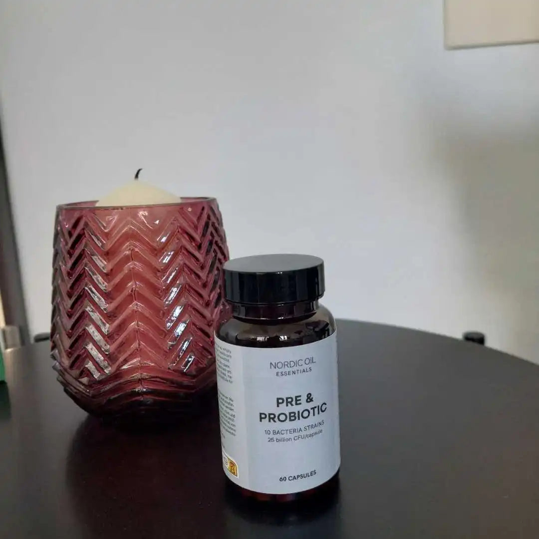 Nordic Oil Essentials Pre & Probiotic kosttilskud i flaske ved siden af en pink zigzag-glaslygte