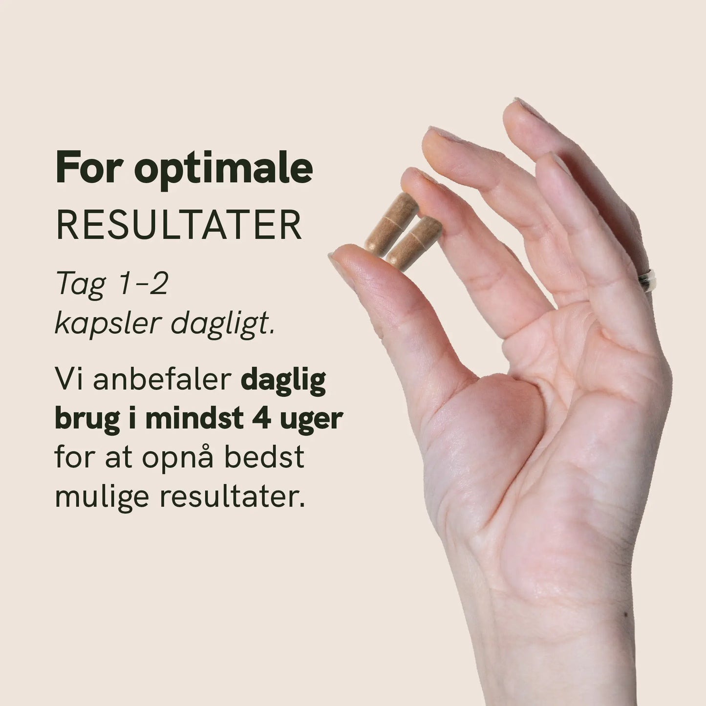 Hånd der holder to kapsler mellem fingrene på en beige baggrund