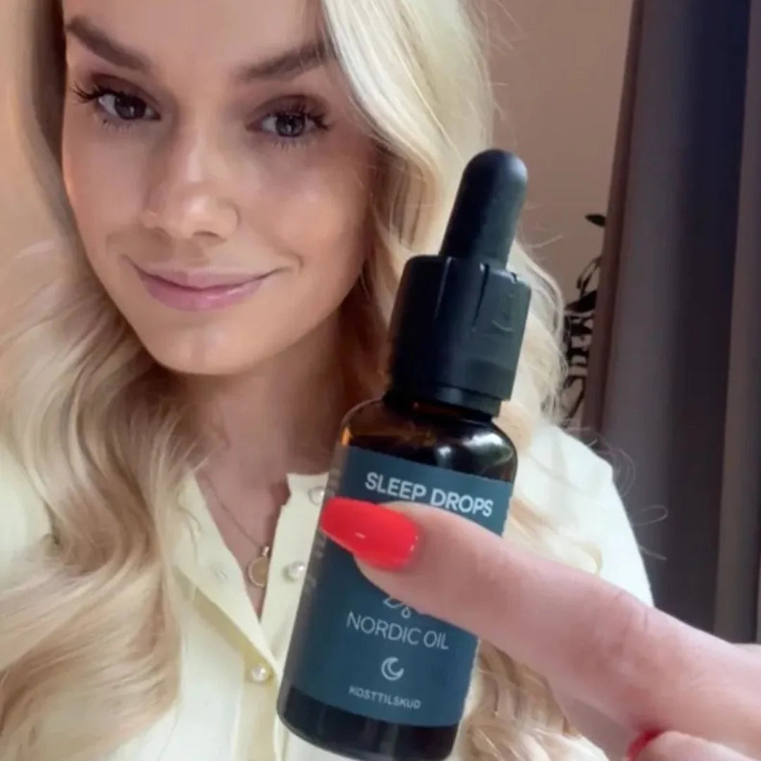 Kvinde viser en mørk glasflaske med pipette mærket Sleep Drops fra Nordic Oil.