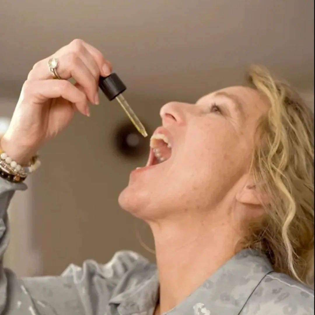 Kvinde der doserer CBD-olie med pipette i munden.