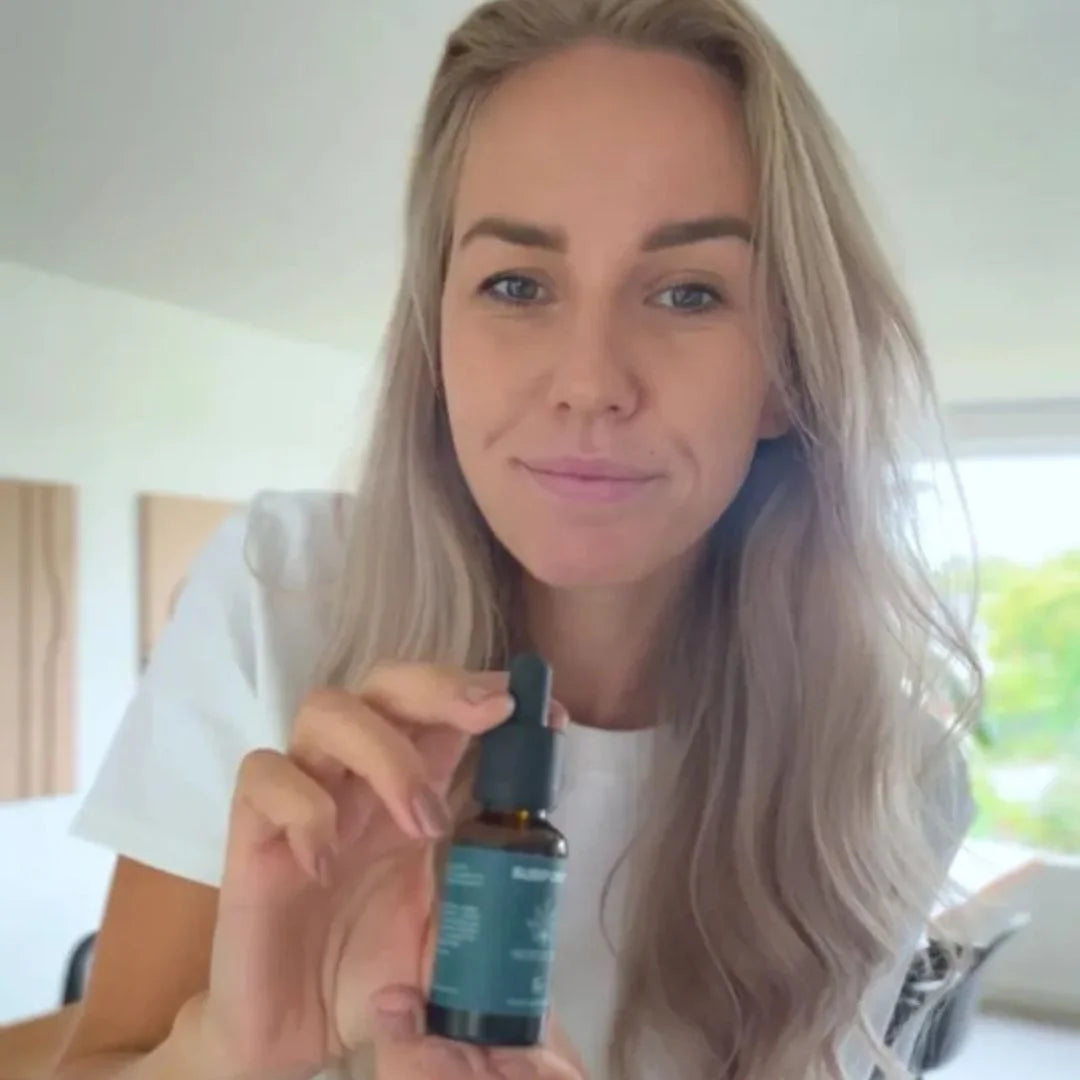 Kvinde viser en flaske CBD-olie med dropper.