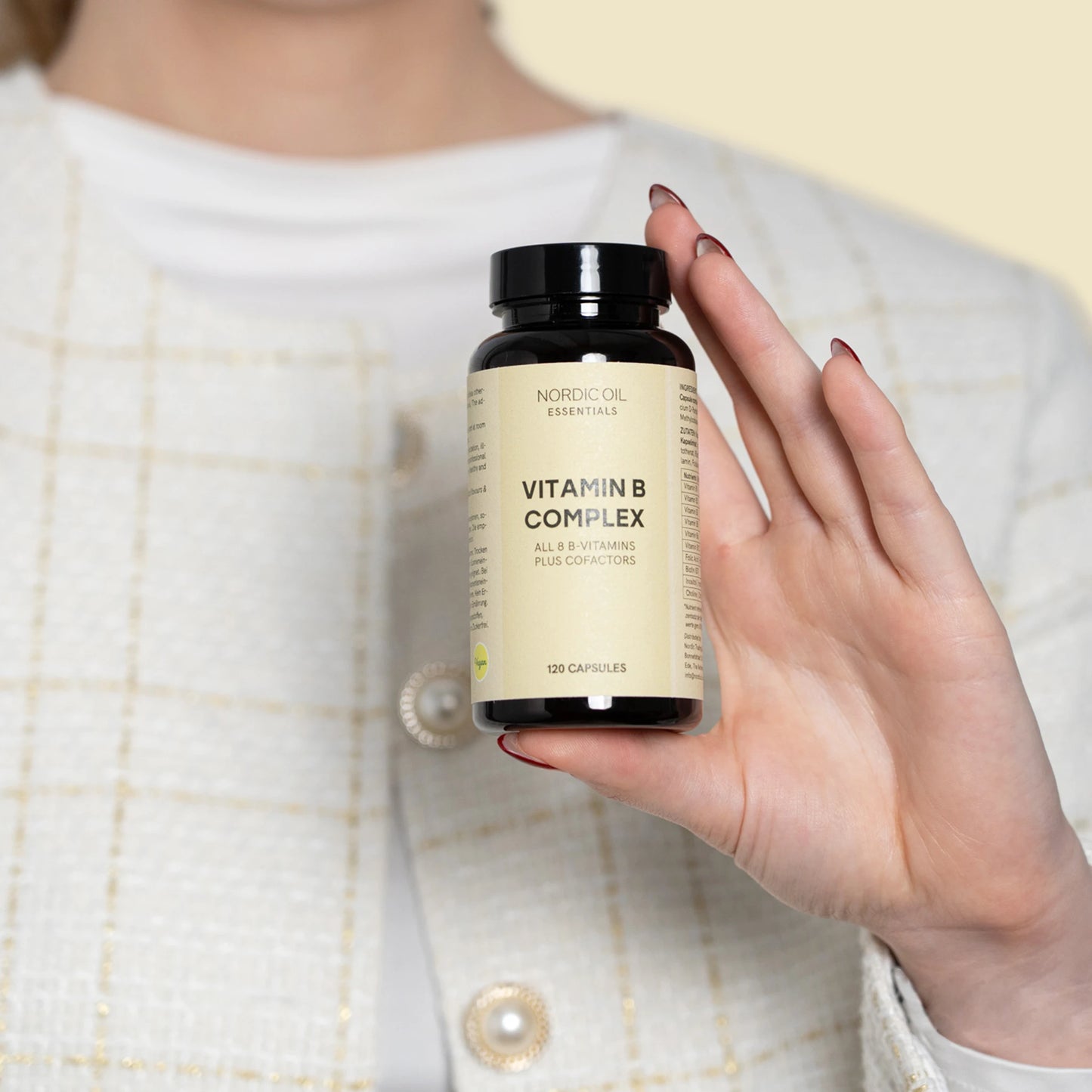 Nordic Oil Essentials Vitamin B Complex kosttilskud i en mørk flaske holdes af en hånd
