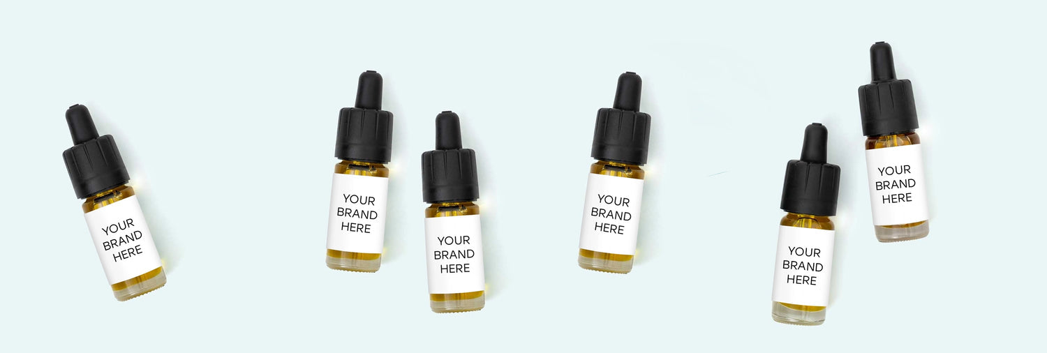 Flere dropperflasker med sorte låg og etiketter med teksten 'Your Brand Here' på en lyseblå baggrund
